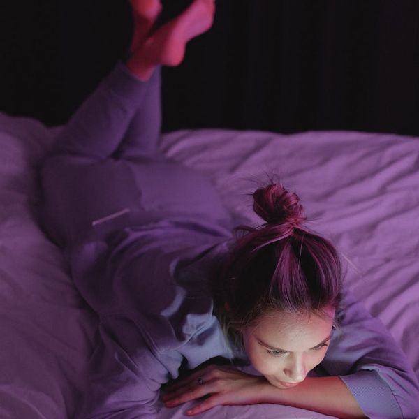 A woman stretching gracefully, silhouetted against a soft pink glow.